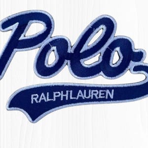 May include: A navy blue embroidered patch featuring the word "Polo" in a cursive script, with a white outline. Below, a navy banner displays "RALPH LAUREN" in white capital letters. The patch is likely for apparel.