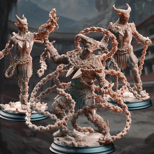 Könnte beinhalten: Drei detaillierte Figuren von gehörnten, humanoiden Kreaturen mit aufwendiger Rüstung und kettenartigen Anhängseln. Die Figuren sind dynamisch posiert, was Action suggeriert, und auf schwarzen Sockeln montiert. Die Farbpalette ist hauptsächlich beige und braun, mit scharfen, stacheligen Details.