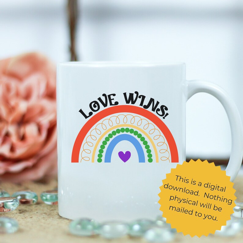K&ouml;nnte beinhalten: Eine wei&szlig;e Keramiktasse mit einem Regenbogen-Design und dem aufgedruckten Text "LOVE WINS!" Der Regenbogen besteht aus gelben, gr&uuml;nen, blauen und violetten Streifen mit einem kleinen violetten Herzen in der Mitte.