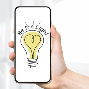 May include: A smartphone displaying a light bulb with a heart shape inside and the text "Be the Light" on a white background.