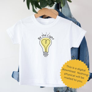 May include: White t-shirt with a black and yellow lightbulb graphic and the text "Be the Light".