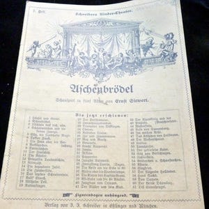 Könnte beinhalten: Altes deutsches Theaterplakat für "Aschenbrödel" (Aschenputtel) von Ernst Siewert, mit einer detaillierten Illustration einer Theaterszene und Cherubinen. Der Text listet verschiedene Stücke auf. Das Papier hat ein blau-weißes Farbschema.