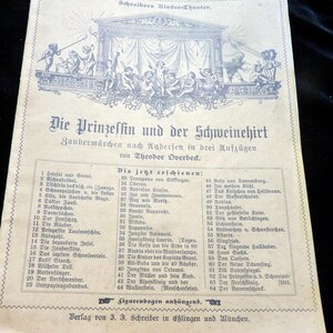 Könnte beinhalten: Ein Vintage-Buchcover mit dem Titel "Die Prinzessin und der Schweinehirt" von Theodor Overbeck. Das Cover zeigt eine Illustration einer Bühne mit Figuren und Text in deutscher Sprache.