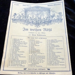 Könnte beinhalten: Eine alte gedruckte Seite eines deutschen Kindertheater-Programms mit einer detaillierten Illustration einer Bühnenszene mit Figuren. Der Text ist auf Deutsch und listet Spieletitel und Autoren auf. Das Papier hat einen blauen Rand.