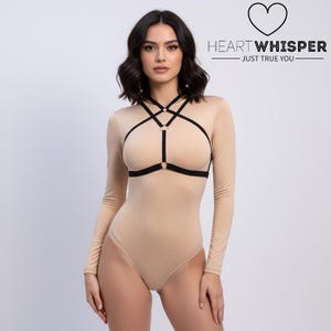 May include: A beige bodysuit with long sleeves and a black harness detail across the chest. The image includes the text "HEART WHISPER - JUST TRUE YOU" in black.
