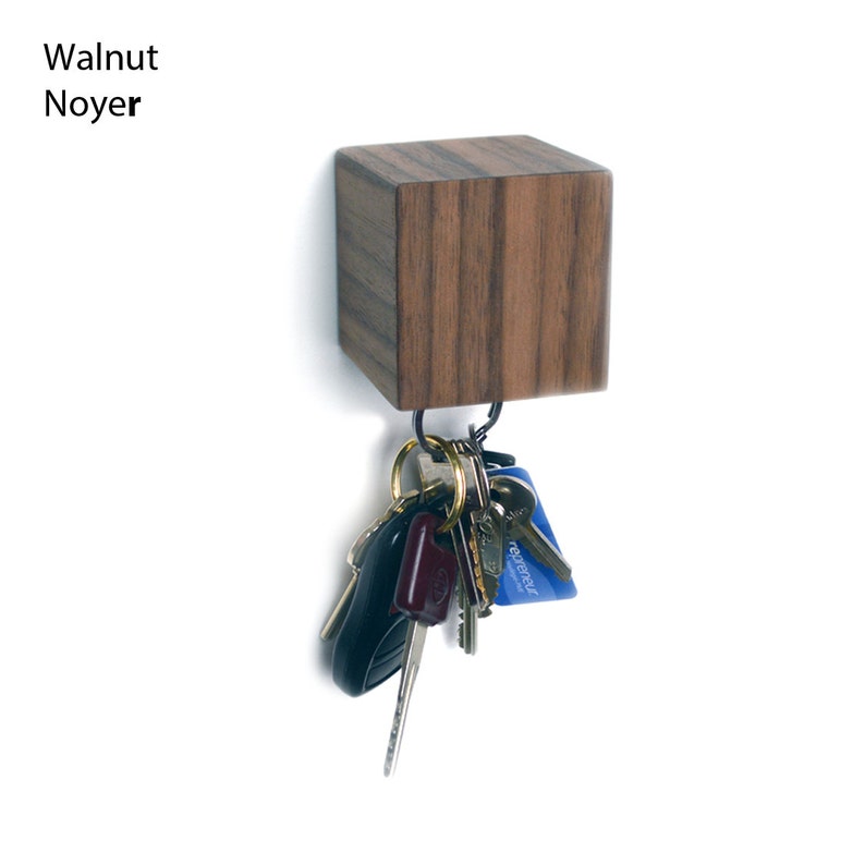 May include: Walnut wood key holder with a square shape and a metal hook. A set of keys are hanging from the hook.