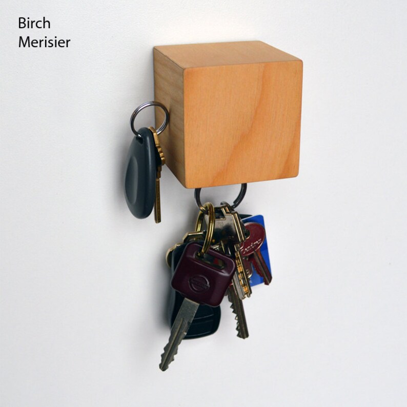 May include: A wooden key holder with a square shape and a natural wood finish. A set of keys is hanging from the holder.