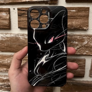 Op de afbeelding: Zwarte telefoonhoes met een gestileerde illustratie van een wezen met roze ogen en witte accenten. Het ontwerp is geplaatst tegen een zwarte achtergrond. De hoes heeft uitsparingen voor de camera en andere telefoonfuncties.