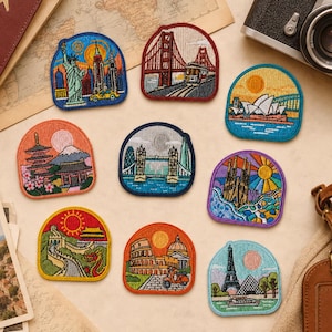 Puede incluir: Una colección de nueve parches bordados que presentan monumentos icónicos mundiales, incluyendo la Estatua de la Libertad, el puente Golden Gate, la Ópera de Sídney, el monte Fuji, el Tower Bridge, la Sagrada Familia, la Gran Muralla y la Torre Eiffel.