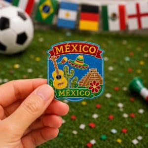 Puede incluir: Un parche bordado azul con la palabra MÉXICO en letras rojas y verdes. El diseño incluye una guitarra amarilla, un sombrero colorido, un cactus verde, una pirámide marrón y una flor roja. El parche tiene forma de escudo con bordes definidos.
