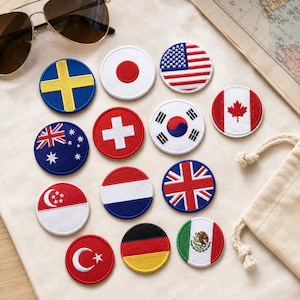 Pode incluir: Uma coleção de catorze emblemas bordados circulares apresentando várias bandeiras nacionais, incluindo Suécia, Japão, Estados Unidos, Austrália, Suíça, Coreia do Sul, Canadá, Singapura, Países Baixos, Reino Unido, Turquia, Alemanha e México.