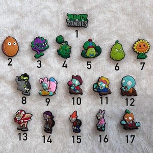 May include: A selection of seventeen colourful Plants vs. Zombies character charms. The charms feature various plant and zombie designs, including a sunflower, a zombie with a newspaper, and a zombie with a pumpkin head. The charms are numbered 1-17.
