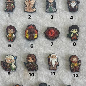 May include: A collection of 15 character-themed charms, featuring various fantasy figures. The charms are in a variety of colors, including brown, green, and gold. Each charm is numbered from 1 to 15.
