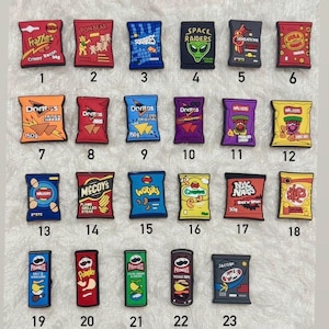 May include: A collection of 23 colorful snack-themed charms, including bags of chips and crisps. Brands include Doritos, Walkers, Pringles, and others. Each charm is a miniature replica of the original packaging.