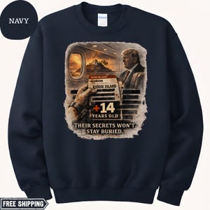 May include: Navy blue sweatshirt with a graphic featuring a boarding pass to "Kiddie Island" and the text "+14 YEARS OLD THEIR SECRETS WON'T STAY BURIED." The design includes an illustration of a person and a sunset.