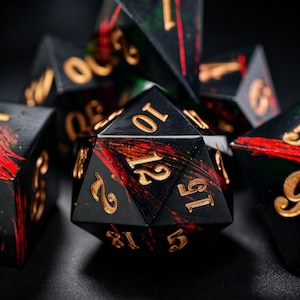 May include: A set of polyhedral dice with a black base, red and green streaks, and gold numbering. These dice are designed for tabletop role-playing games and are set against a dark background.
