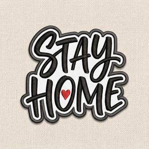 May include: Embroidered patch with the words "STAY HOME" in black script and block letters, outlined in white and black. A small red heart replaces the letter "O" in "HOME". The patch is on a beige fabric background.