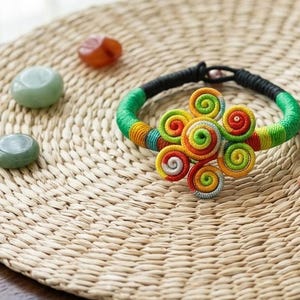 Ręcznie robiona bransoletka pleciona z woskowanej nici w stylu boho – etniczna spiralna biżuteria z motywem kwiatowym