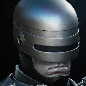 Puede incluir: Primer plano de un casco futurista plateado con una visera oscura. El casco tiene una superficie texturizada y forma parte de un traje m&aacute;s grande. La imagen muestra parte de un rostro con tez p&aacute;lida y expresi&oacute;n seria, evocando un tema de ciencia ficci&oacute;n.