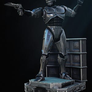 Puede incluir: Una figura de acci&oacute;n de RoboCop de color gris met&aacute;lico, posando con una pistola en una mano y la otra mano levantada. La figura se encuentra sobre una plataforma con una superficie azul, con una pila de contenedores de almacenamiento grises detr&aacute;s.