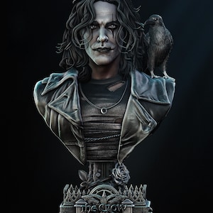 Puede incluir: Busto detallado de un personaje con piel pálida, cabello oscuro y maquillaje de ojos negro, con una chaqueta de cuero y un cuervo en el hombro. La base tiene el texto "THE CROW" y "IN MEMORY OF BRANDON LEE".