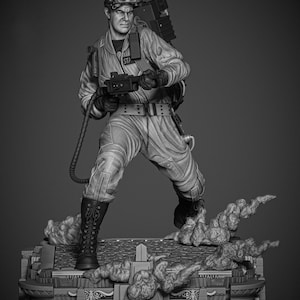 May include: A grayscale figurine of a Ghostbuster in a jumpsuit, boots, and equipment, holding a proton pack and a weapon. The figure stands on a detailed base with smoke effects, capturing a dynamic action pose. The word "STA" is visible on the uniform.
