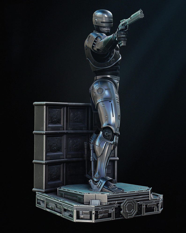 Puede incluir: Estatua detallada de Robocop, una figura plateada y negra en una pose din&aacute;mica, sosteniendo un arma. La estatua tiene intrincados detalles de armadura y se alza sobre una plataforma con un dise&ntilde;o futurista, sobre un fondo oscuro.