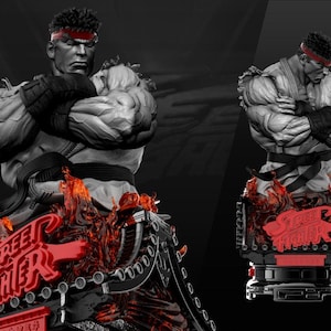 Op de afbeelding: Grijswaarden standbeeld van een gespierde mannelijke figuur met een rode hoofdband en zwarte handschoenen, armen gekruist. De basis heeft rode vlammen en de woorden "Street Fighter" in het rood. Het beeld staat tegen een donkere achtergrond.
