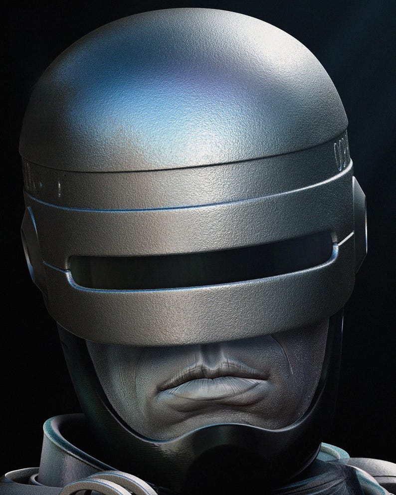 Puede incluir: Primer plano de un casco plateado met&aacute;lico con visera y parte superior redondeada. El casco tiene un dise&ntilde;o futurista, con un fondo oscuro. La cara de una persona es visible debajo de la visera.
