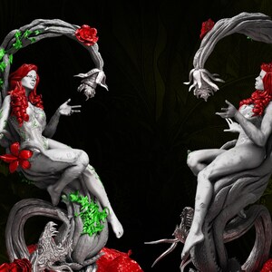 May include: Two statues of a woman with red hair and a floral design, seated on a tree branch. The statues are gray with red and green accents. The background is dark with green foliage.