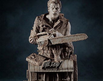 Op de afbeelding: Gedetailleerde buste sculptuur van een man met een kettingzaag, met de tekst "EVIL DEAD 2 DEAD BY DAWN" op een miniatuur huisbasis. De sculptuur is in grijstinten en bruin, met ingewikkelde details.