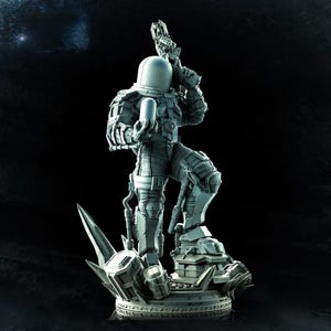 May include: A detailed gray figurine of a character in a futuristic spacesuit, holding a weapon and a cylindrical object. The figure stands on a detailed base with sharp, angular elements. The overall design suggests a science fiction or fantasy theme.