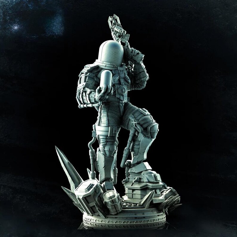 May include: A detailed gray figurine of a character in a futuristic spacesuit, holding a weapon and a cylindrical object. The figure stands on a detailed base with sharp, angular elements. The overall design suggests a science fiction or fantasy theme.