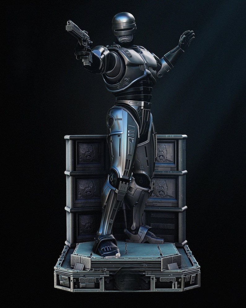 Puede incluir: Estatua met&aacute;lica plateada y azul de RoboCop, sosteniendo un arma en su mano derecha y su mano izquierda levantada. La estatua est&aacute; sobre una plataforma con una base detallada y un fondo oscuro.