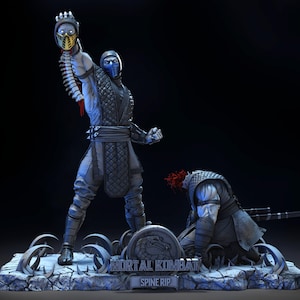 Puede incluir: Estatua detallada que representa una escena de Mortal Kombat, con dos personajes en combate. Una figura sostiene una cabeza cortada, mientras que la otra está arrodillada. La base dice "MORTAL KOMBAT SPINE RIP."