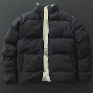 May include: A black puffer jacket with a high collar and a white, fluffy interior lining. The jacket has a quilted design and two side pockets. The jacket is designed for cold weather.