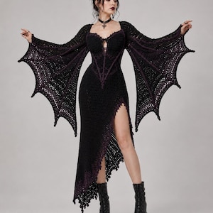May include: A black crochet dress featuring long, wide bat-wing sleeves with purple accents. The bodice has a sweetheart neckline with lace-up detailing, and the skirt includes a high side slit with a jagged, asymmetrical hemline and purple trim.