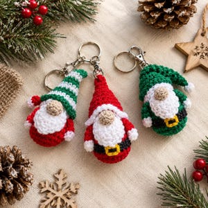 May include: Three crocheted gnome keychains with metal lobster clasps. One gnome wears a green and white striped hat, one wears a solid red hat, and one wears a solid green hat. Each gnome features a white beard, a tan nose, and a black belt.