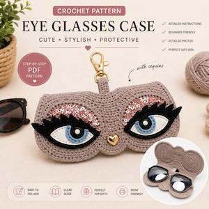 Puede incluir: Un estuche de gafas de ganchillo en color marrón claro, con un diseño caprichoso de ojos grandes con iris azules y párpados con lentejuelas. El estuche tiene un cierre dorado y el texto "EYE GLASSES CASE".