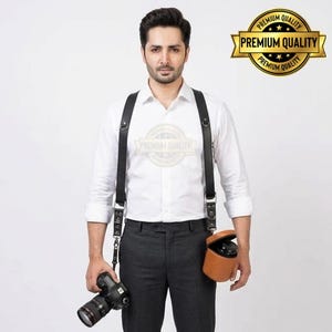 May include: Black leather camera harness with adjustable straps and metal hardware. Includes a brown leather lens case and a DSLR camera. The image also features a gold seal that says "Premium Quality".