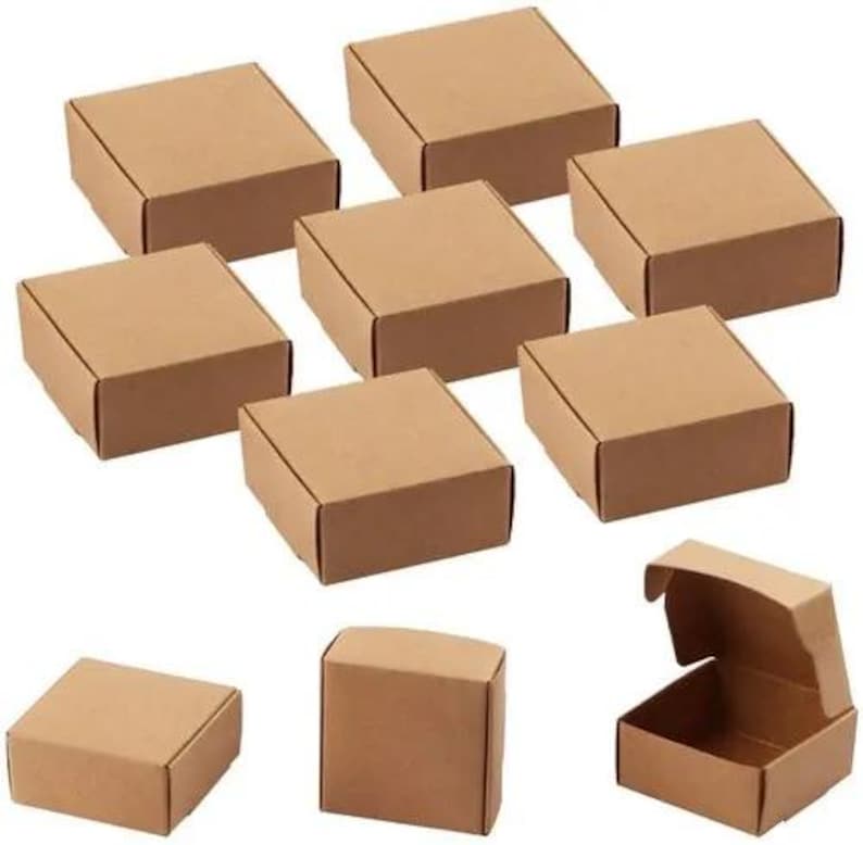 May include: A collection of small, square, brown cardboard boxes. Some boxes are closed, while others are open, revealing the interior. The boxes are arranged on a white surface, showcasing their shape and design.