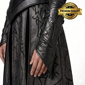 May include: Close-up of a black leather arm guard with buckles and decorative stitching. The arm guard is part of a dark outfit with a patterned skirt. A gold seal with the words "Premium Quality" is visible.