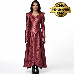 May include: A long, red dress with a V-neck and intricate detailing. The dress features long sleeves and a flared skirt. The shoulders have a structured design, and the dress is paired with black boots. A gold "Premium Quality" seal is in the upper right corner.