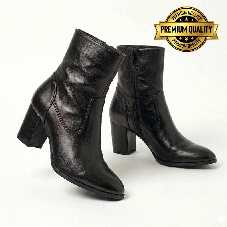 May include: A pair of black leather ankle boots with block heels. The boots have a side zipper and a rounded toe. The boots are displayed on a white background. A gold seal with the words "Premium Quality" is in the upper right corner.