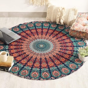 Könnte beinhalten: Ein rundes Mandala-Wandteppich in Marineblau mit einem detaillierten, symmetrischen Design in Türkis, Orange und Rot. Ein Laptop, eine Tasse und Bücher liegen auf dem Wandteppich. Dekorative Kissen und eine kleine Pflanze sind ebenfalls zu sehen.
