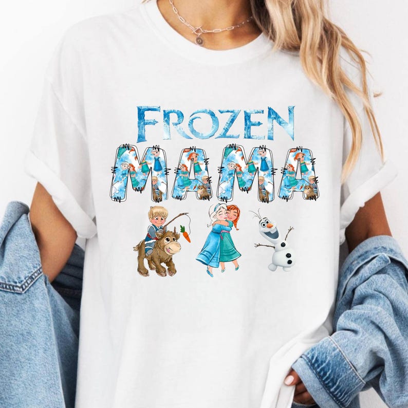 Pu&ograve; includere: T-shirt bianca con la scritta "FROZEN MAMA" in blu, con illustrazioni dei personaggi del film Frozen. La maglietta ha girocollo e maniche corte. Il design include immagini di Anna, Elsa, Olaf e Kristoff.
