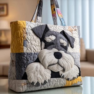 May include: A quilted tote bag with a Schnauzer dog design. The bag is made from fabric squares in grey, yellow, and white. The dog's face is the focal point, with textured details. The handles are patterned with a variety of colours.