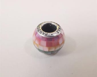 May include: A colorful bead with a mosaic design. The bead features a mix of pink, yellow, and green hues. The top of the bead has the word "PANDORA" engraved on it. This bead is likely a charm for a bracelet or necklace.