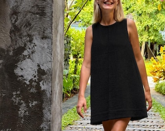 May include: A sleeveless black mini dress with a textured, crinkled fabric finish, a round neckline, and a straight-cut hemline. The garment features a simple, loose-fitting silhouette that falls above the knees, crafted from a lightweight material.