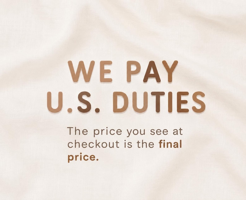 May include: A graphic display on a light cream fabric background featuring the brown text WE PAY U.S. DUTIES in a bold sans-serif font, followed by the smaller text The price you see at checkout is the final price in a matching brown colour.